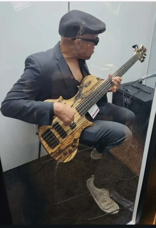 The Scoop LA Publisher, Buddy Sampson, also a bass player, tries out a bass with a futuristic design. Photo by Lamar Webster. 